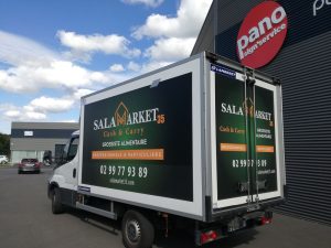 Camion professionnel avec semi-covering publicitaire installé sur l’arrière et les côtés, devant une agence de signalétique.